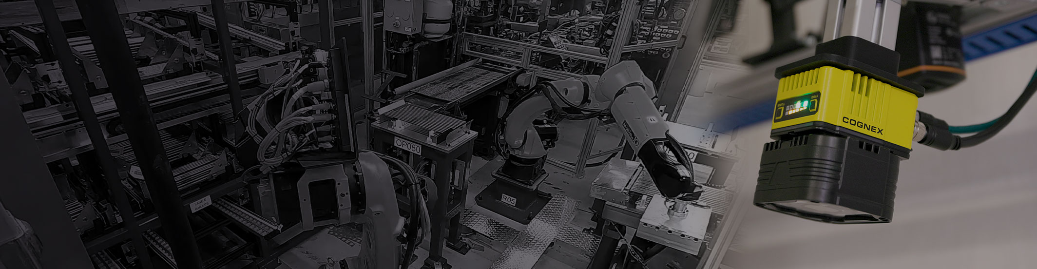 Eine Reihe von Geräten, Drähten und Roboterarmen in einer Fertigungsanlage, mit einem Bildverarbeitungssystem von Cognex im Vordergrund. 